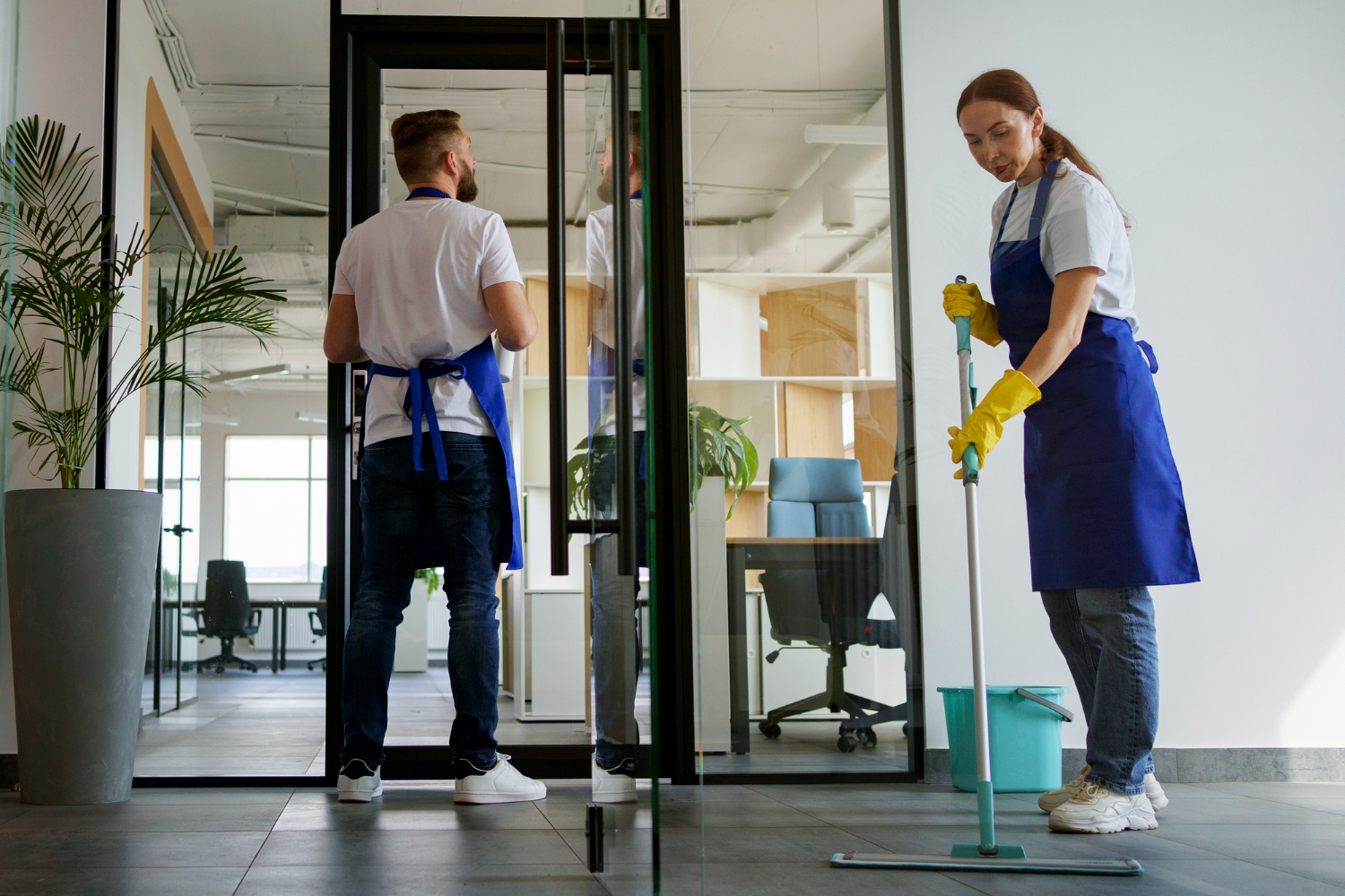 Cleaning team mopping a modern glass-walled office