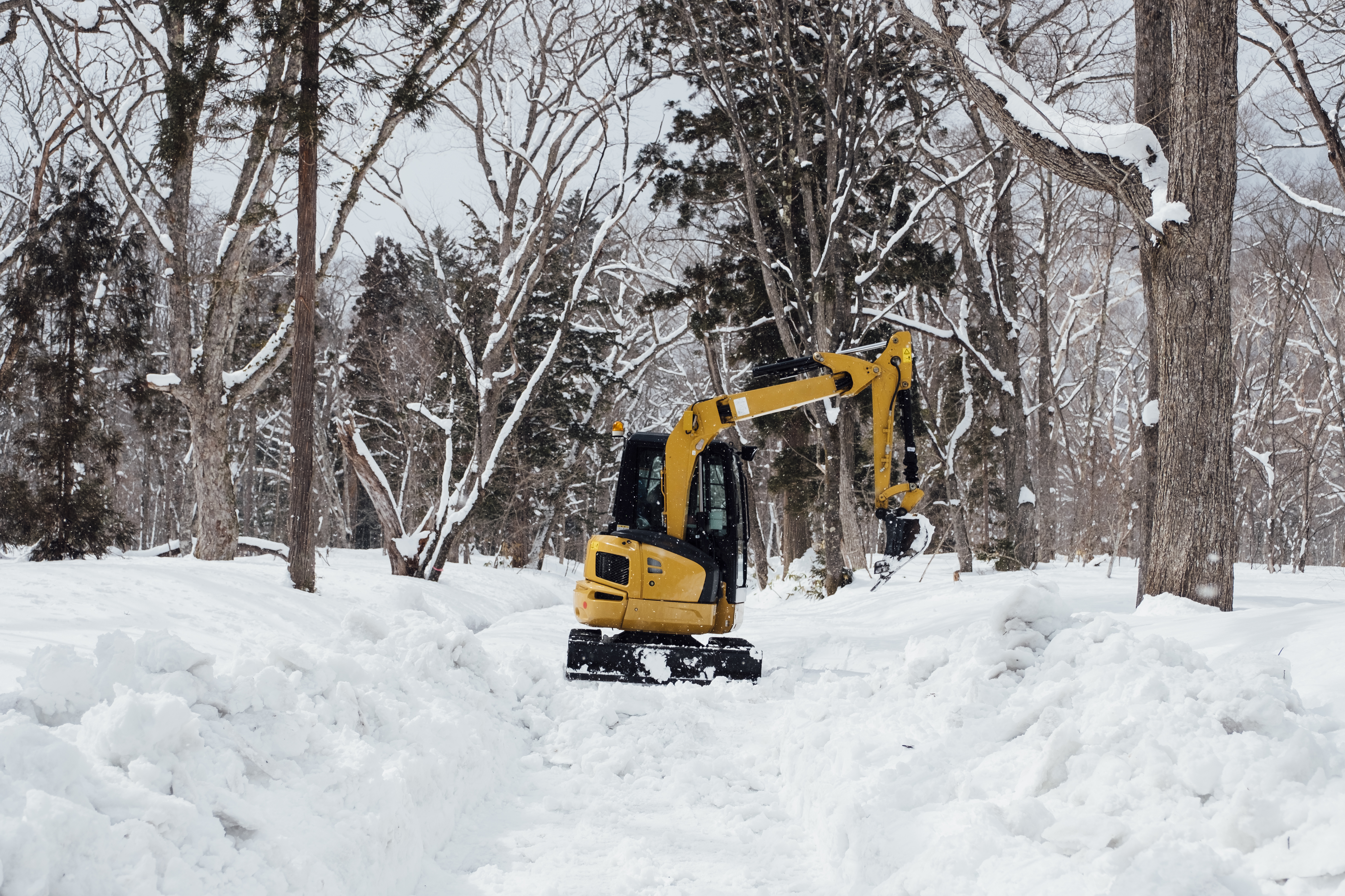 Heavy equipment excavator clearing deep snow accumulation