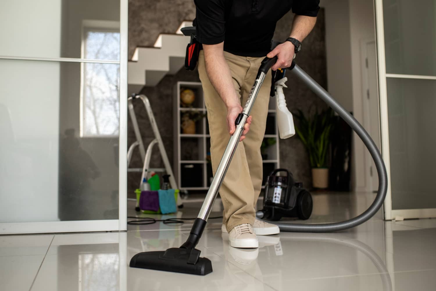 Professional cleaner vacuuming gleaming tiled floor in home