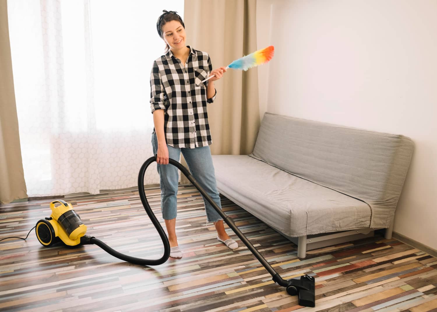 Professional cleaner dusting and vacuuming bright residential space for move-in