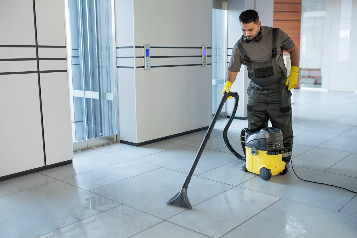 Professional cleaner with industrial vacuum completing post-construction clean in lobby
